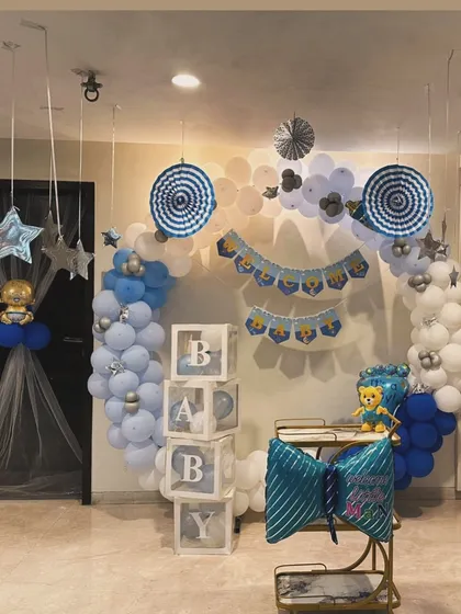 A full room decoration to welcome a baby boy. This setup includes a circular balloon arch, "BABY" blocks, and other themed elements in a cohesive blue and white color scheme.