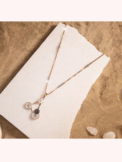 A delicate Y-necklace in rose gold with black and white circular CZ diamond charms.