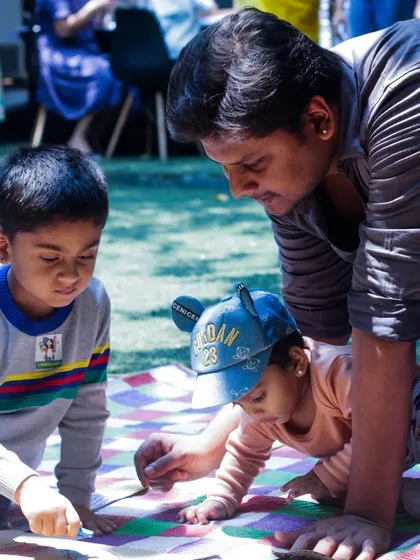 A heartwarming moment from our Father's Day event, with a dad and his two little ones working on a craft together on the grass. My events are designed to foster connection and create lasting family memories.