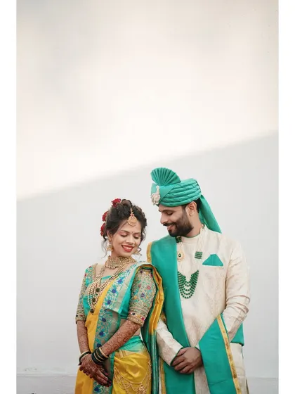 A beautifully composed portrait against a clean, minimalist background. This allows the couple's vibrant attire and happy expressions to be the complete focus.