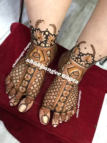 A classic bridal foot design featuring jhumkas and floral patterns. The intricate checkerboard design on the toes adds a beautiful finishing touch.