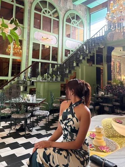 A seated pose, showing the dress in a different context and capturing the beautiful restaurant decor.