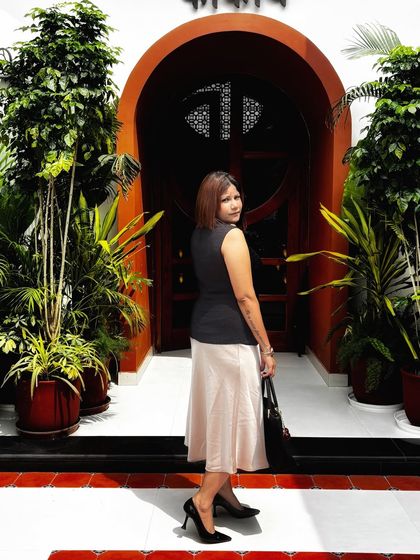 Another angle of this polished ensemble. The clean lines of the vest and skirt, paired with classic accessories, create a look of understated sophistication.