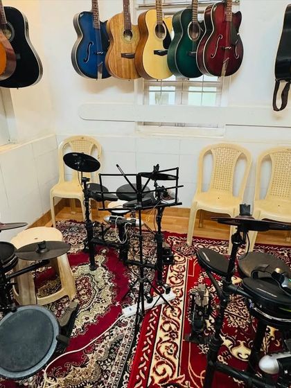 Our drum room, equipped with multiple electronic kits and surrounded by guitars. This space is designed for both individual practice and energetic group rhythm sessions.