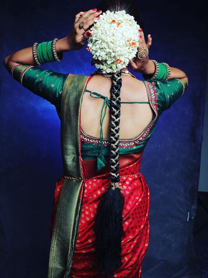 The back view of a classic bridal hairstyle, featuring a thick braid and a full circle of fresh jasmine flowers. This is a quintessential look for any South Indian bride.