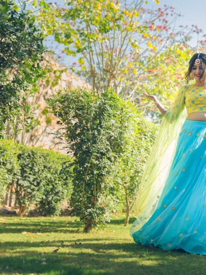 A bride in a vibrant Mehendi outfit, dancing joyfully in a garden. This shot is full of life, color, and the happy energy of pre-wedding festivities.