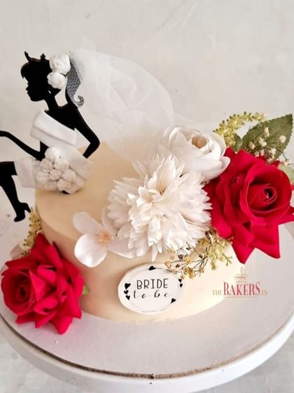 A classic red and white bachelorette cake for a bride-to-be. The design features a silhouette topper with a real tulle veil, surrounded by beautiful red and white roses.