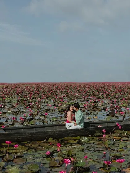A wide shot showing the vastness of the lotus lake in Kerala. This image captures the scale of the beautiful landscape, with the couple enjoying a peaceful boat ride together.