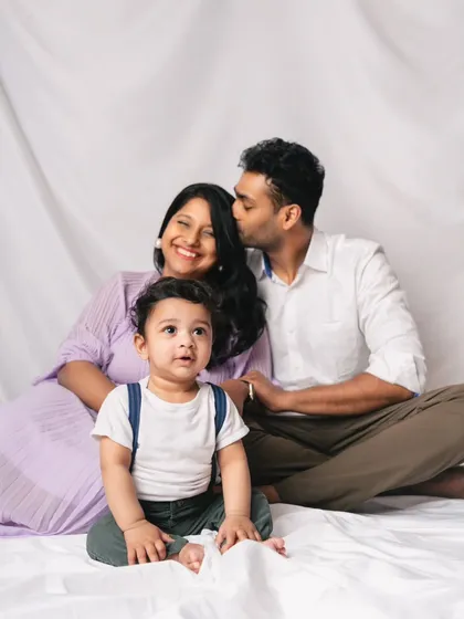 A candid family moment. While the baby looks on, the parents share a happy, loving glance, showing the strong foundation of their family.