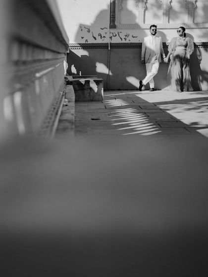 A creatively framed black and white shot using a low angle and foreground blur. The dramatic shadows and composition give this heritage portrait an artistic and edgy feel.