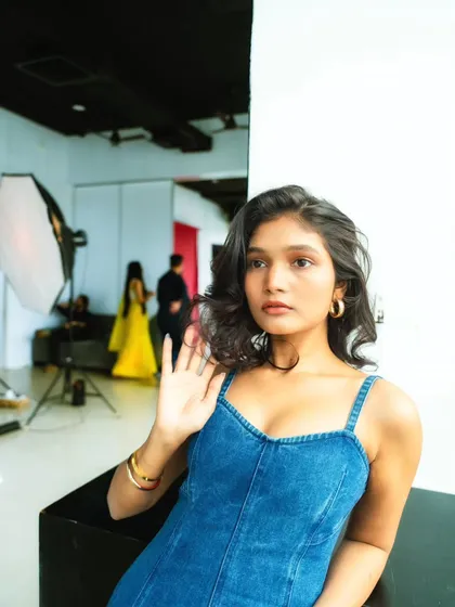 A candid, off-guard moment in the studio. You can see the lighting setup in the background, which gives a glimpse into the creative process.