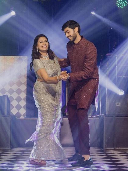 A heartwarming mother-son dance, full of love and smiles, under the bright lights of the sangeet stage.