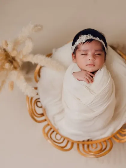 A duplicate of image 37, this angle provides a clear view of the swaddled newborn in the cane prop. These posed shots are taken with the utmost care to ensure the baby is safe and comfortable.