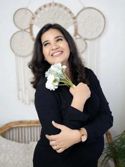 A beautiful solo portrait of the mother-to-be, looking up with a hopeful smile. The simple black dress and the soft lighting of the boho setup create a lovely, natural look.