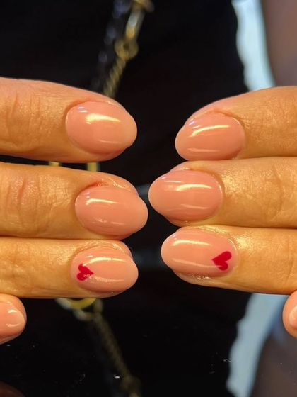 A simple and sweet manicure with a sheer pink polish and a tiny red heart accent on one nail.
