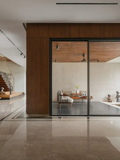 This wide view of Villa Shakthi highlights the open-plan layout and the visual connections between different zones. The polished marble floor reflects light throughout the ground level, enhancing the sense of space and fluidity from the foyer to the living areas.