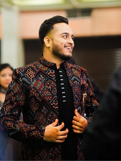 A candid shot of the groom during his Sangeet. The intricate, colorful jacket is a fantastic choice for a night of music and dance.