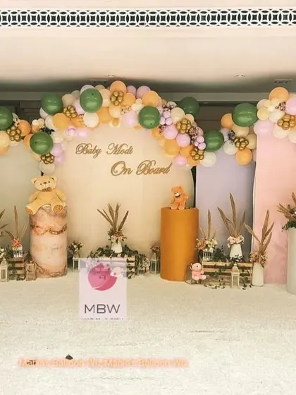 A sophisticated "Baby Modi On Board" baby shower with a modern, earthy color palette. The setup features teddy bears, pampas grass, and a stylish balloon garland.