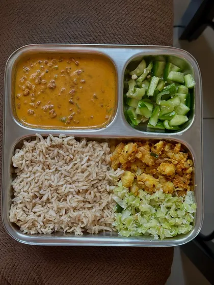 A balanced meal of brown rice, horse gram curry, and a variety of sautéed vegetables. Horse gram is a highly nutritious and protein-rich legume.
