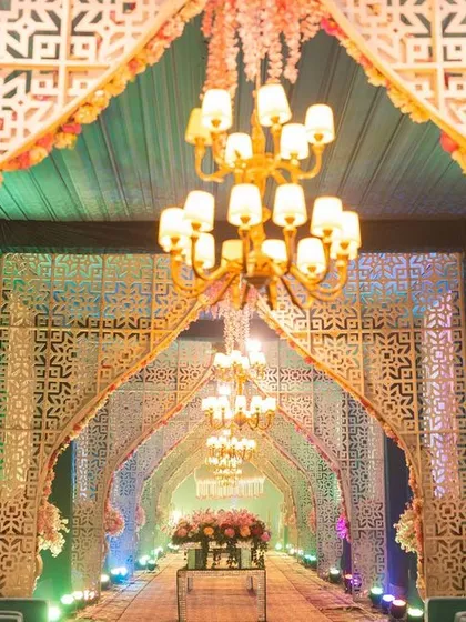 We designed this spectacular entrance walkway for a grand Sangeet night. A series of repeating white jaali arches, illuminated by elegant chandeliers and soft uplighting, creates a dramatic and awe-inspiring path for guests to enter the main event area.