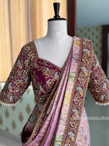 A regal bridal half-saree in shades of maroon and lavender. The blouse is heavily embroidered with zardosi work in a traditional peacock motif, perfectly complementing the woven silk of the saree.