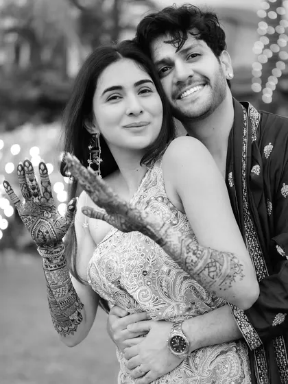 A fun black and white shot of Rupanshi and Yash. She is playfully showing off her intricate mehndi, and their smiles are completely genuine.