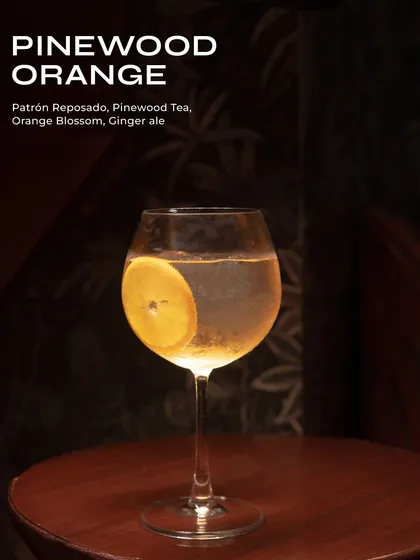 The Pinewood Orange, a refreshing and aromatic gin cocktail. Patrón Reposado is mixed with pinewood tea, orange blossom, and ginger ale for a complex, bubbly drink.