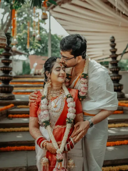 A tender kiss on the forehead, a blessing from the groom to his bride, surrounded by the beauty of their traditional wedding decor.