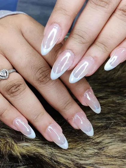 A sheer white manicure with a pearlescent chrome finish on long almond extensions.