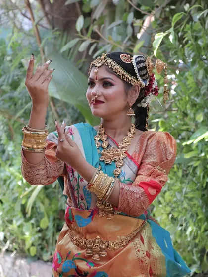 A candid shot of the bride in a dance pose, showing the movement and flow of her beautiful saree.