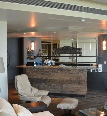 Another angle of the Magnolias apartment, showing the open-concept living and bar area. The bar, crafted from a single piece of reclaimed wood, serves as a stunning focal point, while the mirrored back wall enhances the sense of space and light.
