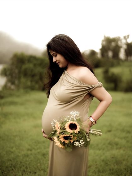 A beautiful three-quarter portrait of the mom-to-be looking down at her bump, holding a bouquet of sunflowers. The soft light and her gentle expression are perfect.
