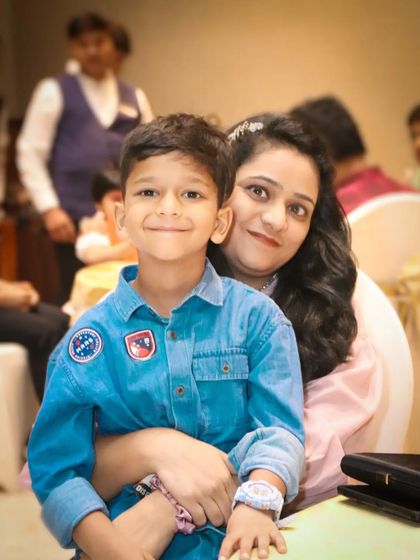 A mother and her son share a sweet moment, with the boy sitting comfortably in her lap. The soft focus and warm lighting create a gentle, loving portrait.