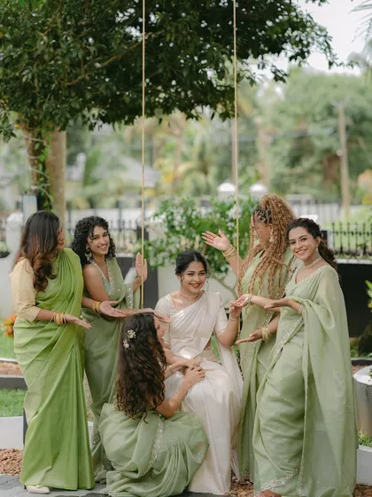 The bride, seated on a swing, is surrounded by her smiling bridesmaids. This candid and interactive group photo is full of life and captures the strong bond of their friendship.
