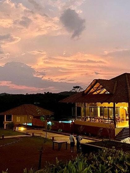 A stunning sunset view over a resort in Sakleshpur, with the main building glowing in the warm evening light.