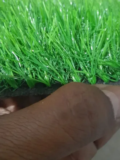 A close up showing the thickness and texture of a 25mm artificial grass sample. You can see the individual blades and the sturdy backing that holds them in place.