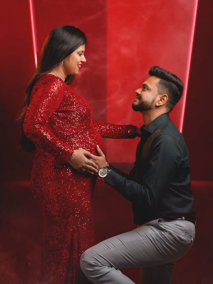 A romantic pose with the dad-to-be looking up lovingly at his partner, both framed by a dramatic red light.