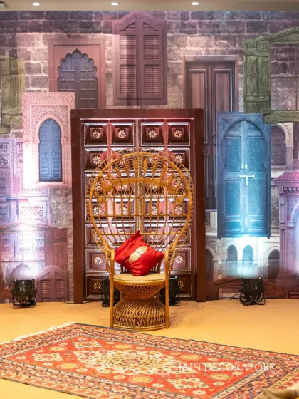 A throne fit for a Mehndi queen. The peacock chair is set against a creative backdrop of printed doors and windows, creating an eclectic and artistic photo corner.