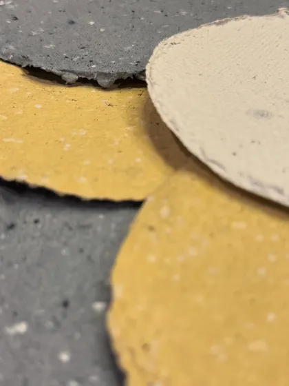 A close-up of finished handmade paper sheets in different natural colors. The texture is beautifully rustic, and the deckle edges add to their handmade charm.