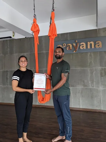 Another graduate receives his certificate, marking the beginning of his journey as an aerial yoga instructor.