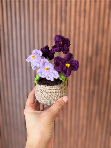 This potted plant features delicate purple and lavender flowers. It's a lovely, maintenance-free way to add a touch of nature to your home.