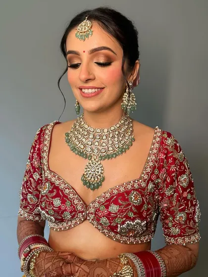 A close-up of the bride's face, showing the soft, shimmery eye makeup and the perfectly blushed cheeks that create a look of cultural splendor.