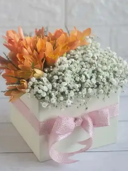 A charming box arrangement of orange lilies and baby's breath, a sweet and simple gift for someone special.
