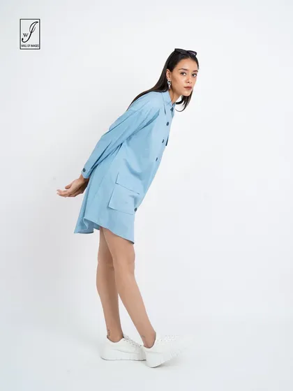 A light blue shirt dress modeled in a studio, with a pose that shows off its casual and comfortable style.