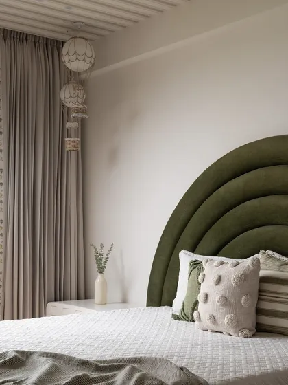 The bed in the kids' room has a custom arched, channel-tufted headboard in a beautiful olive green velvet, creating a cozy and stylish focal point.