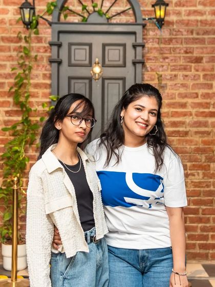 Two friends posing by our famous brick wall and vintage door. It's the perfect backdrop to capture memories of a great night out.