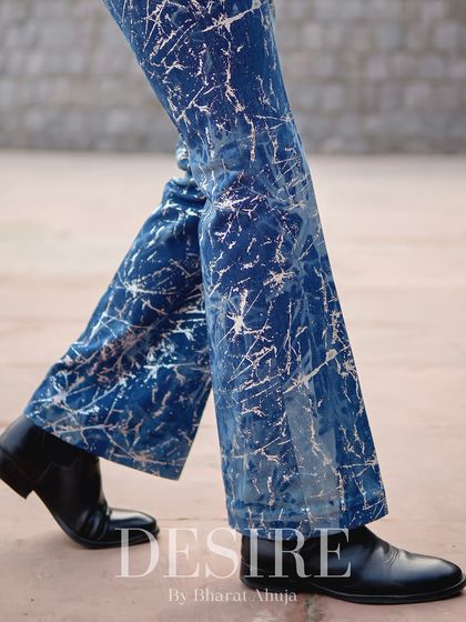 A detail shot of the flared trousers from the blue splatter-print suit, showcasing the unique pattern and modern silhouette as it moves.
