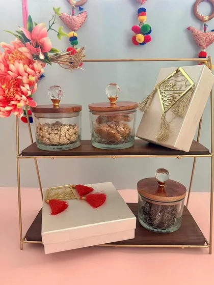 Unbox the joy of Makar Sankranti with this exclusive hamper. It features a two-tiered stand with jars of festive treats and elegant gift boxes, perfect for sharing with loved ones.