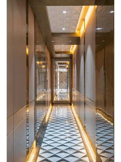 This hallway uses a full-length mirror wall to visually double the space. The geometric floor inlay and cove lighting guide the way, turning a simple corridor into an elegant experience.