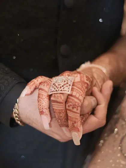 This journey began with a spark. A close-up on the couple's hands, her intricate mehendi, and the beautiful engagement ring.